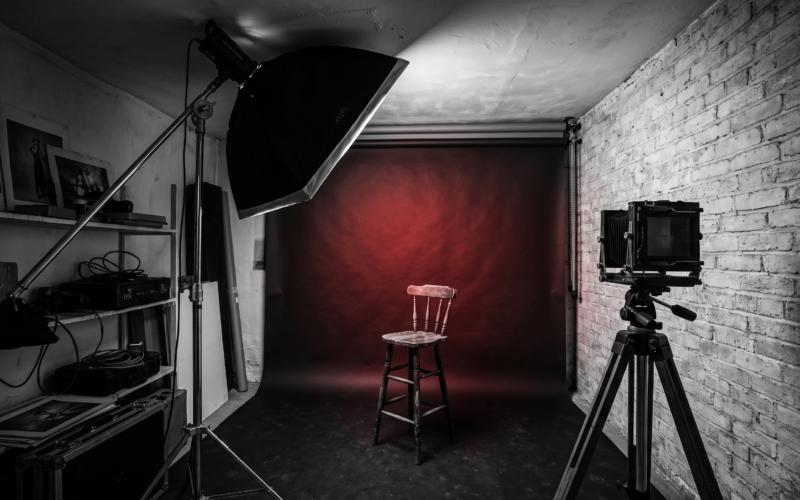 A cramped small photo studio with a low ceiling, a softbox nearly touching it, and a backdrop only a few feet behind an empty stool